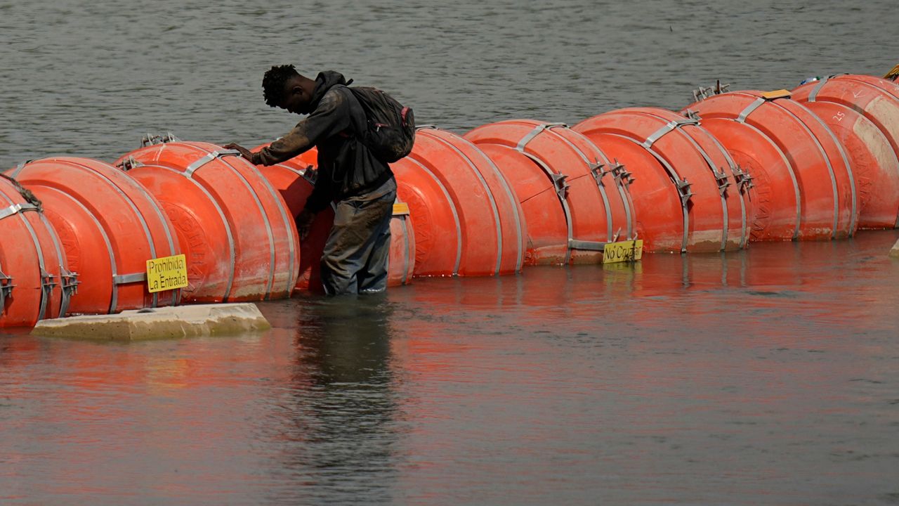 A migrant from Columbia stands at a floating buoy barrier as he looks to cross the Rio Grande from Mexico into the U.S., Monday, Aug. 21, 2023, in Eagle Pass, Texas. (AP Photo/Eric Gay)