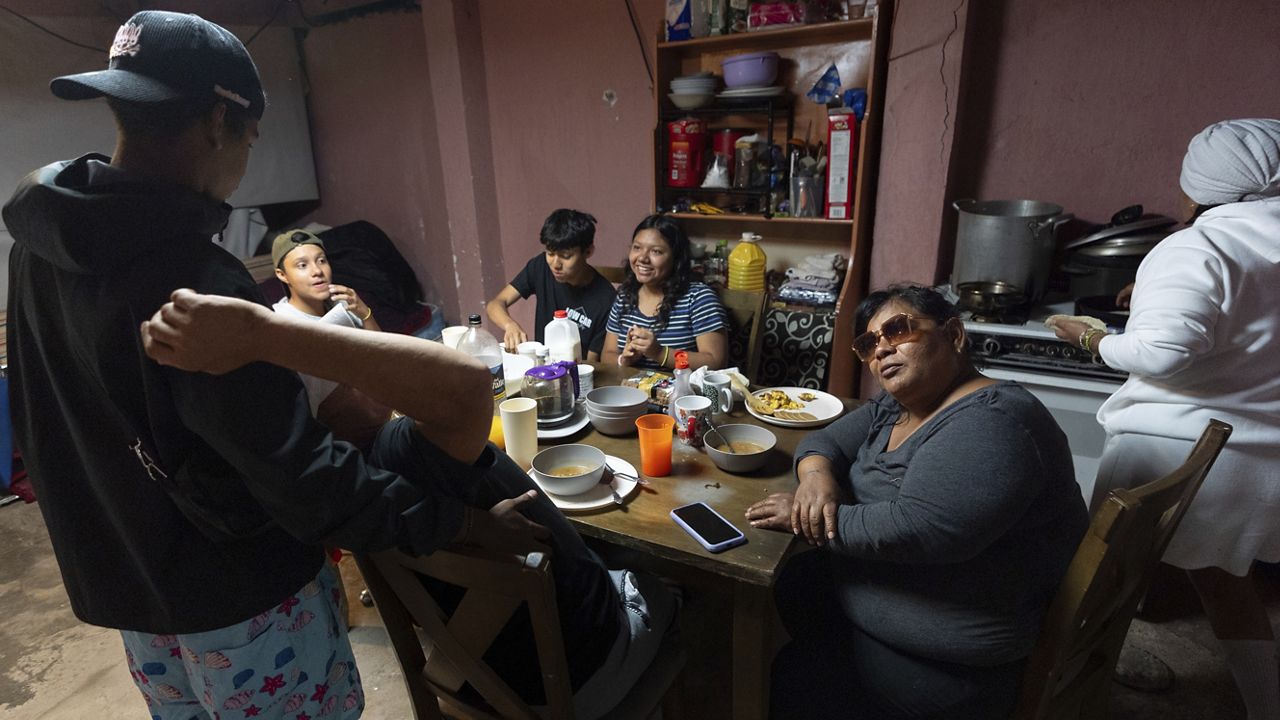 Martha Rosales, right, talks with migrants mainly from Cuba while they wait for an appointment to apply for asylum in the United States through the CBP One app Wednesday, May 22, 2024, in Tijuana, Mexico. (AP Photo/Gregory Bull)