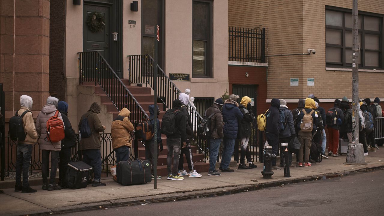 Migrants queue in the cold as they look for a shelter outside a migrant assistance center at St. Brigid Elementary School on Tuesday, Dec. 5, 2023, in New York. (AP Photo/Andres Kudacki, File)