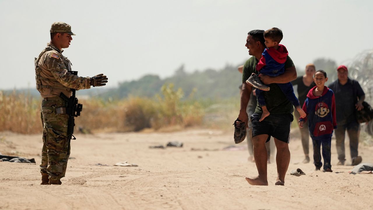 Migrants who crossed the Rio Grande river to the U.S. from Mexico seek direction from a guardsman, Friday, Sept. 22, 2023, in Eagle Pass, Texas. (AP Photo/Eric Gay)