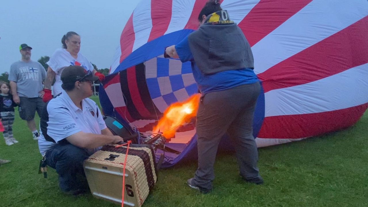 Workers inflate a miniature balloon operated by remote control and owned by Home of the Brave RC Hot Air Balloon Friday morning at Simard-Payne Memorial Park in Lewiston Friday. The smaller balloon was part of the Great Falls Balloon Festival, which runs through Sunday. (Spectrum News/Sean Murphy)