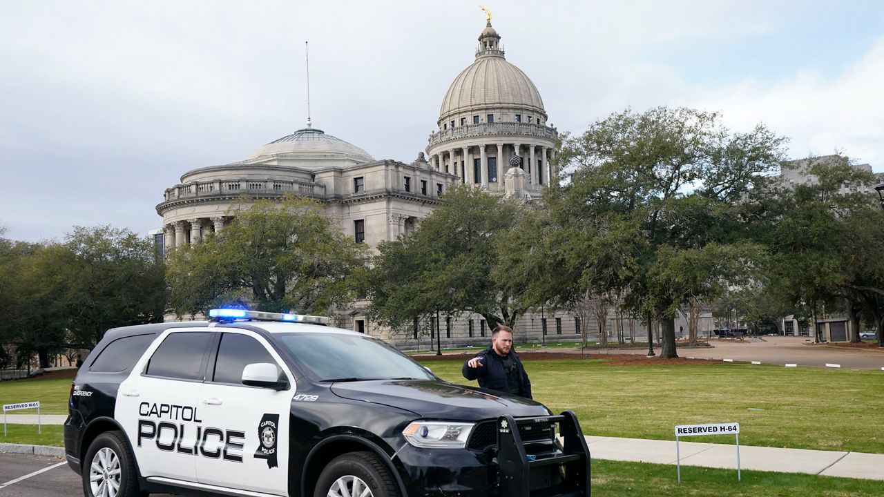 A Capitol Police officer warns off passersby as they respond to a bomb threat at the Mississippi State Capitol in Jackson, Miss., Wednesday morning, Jan. 3, 2024. The building was emptied, the grounds cleared of vehicles as officers investigated. (AP Photo/Rogelio V. Solis)