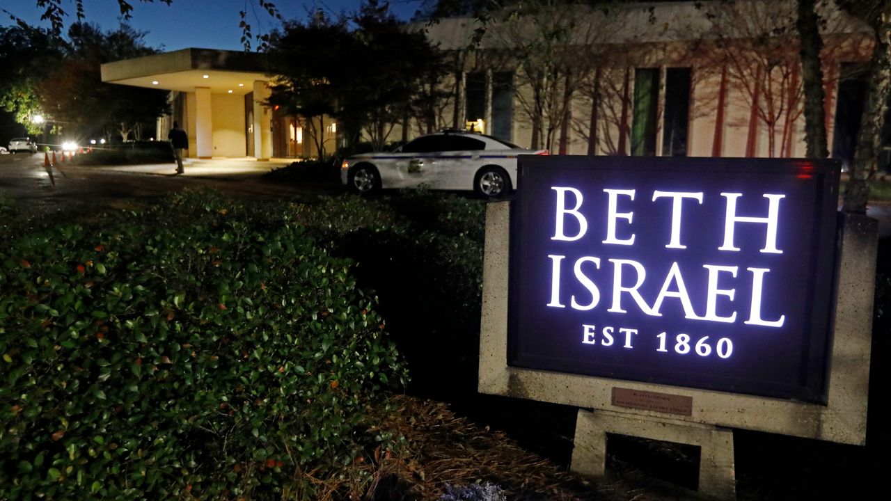 An armed sheriff's deputy sits outside the Beth Israel Congregation synagogue in Jackson, Miss., on Nov. 2, 2018. Over the weekend, the synagogue was one of hundreds of Jewish institutions in the U.S. to be targeted by bomb threats. (AP Photo/Rogelio V. Solis)