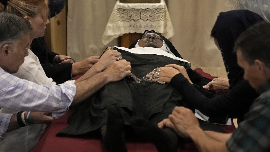 People pray over the body of Sister Wilhelmina Lancaster at the Benedictines of Mary near Gower, Mo. 