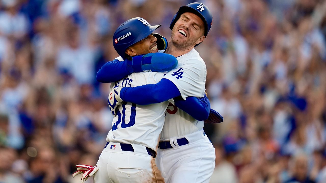 Los Angeles Dodgers' Freddie Freeman, right, and Mookie Betts celebrate after they scored on a single by Max Muncy during the first inning in Game 1 of a baseball NL Championship Series against the New York Mets, Sunday, Oct. 13, 2024, in Los Angeles. (AP Photo/Gregory Bull)