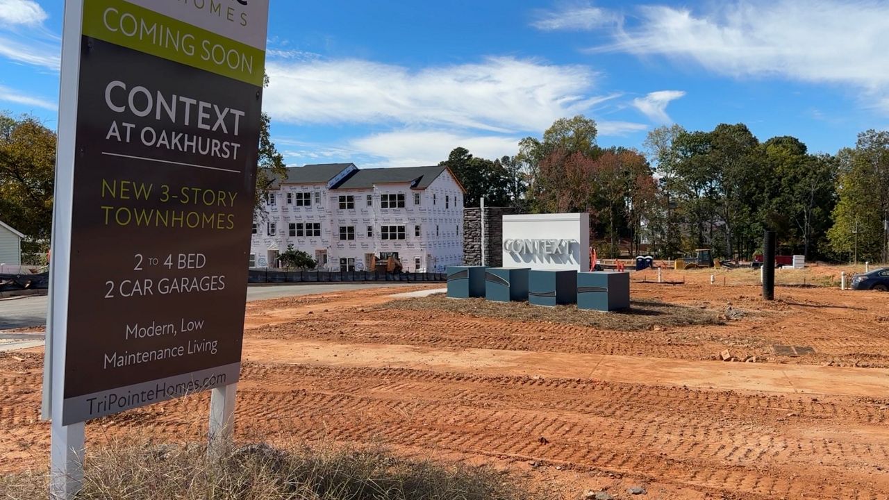 A 'Context at Oakhurst' coming soon sign in the foreground, under-construction townhome building in the background of a construction site