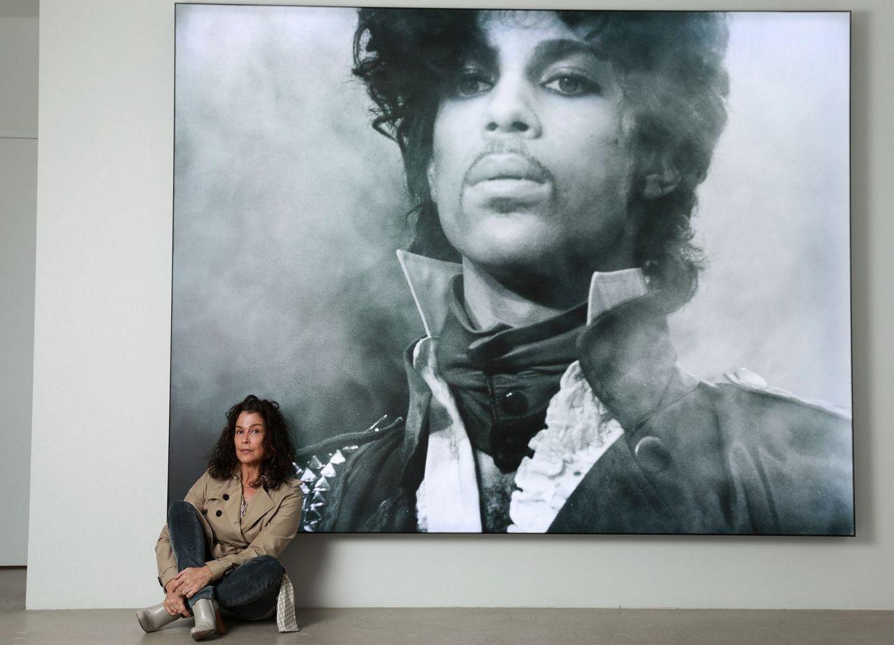 Susannah Melvoin poses next to a photo of Prince at Warner Music Group in L...