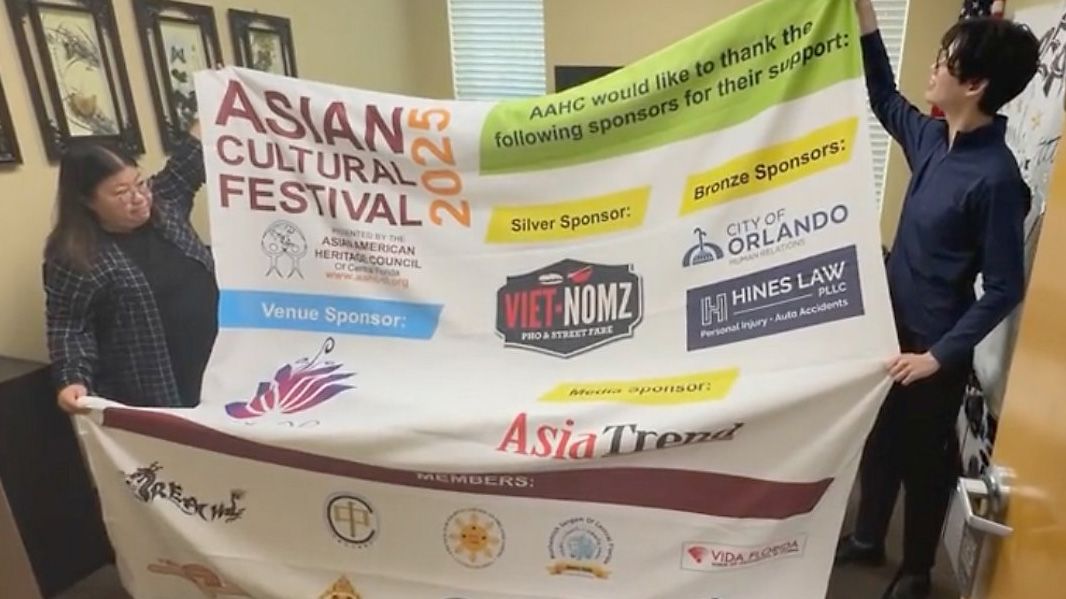 R.E.A.C.H. Chair Pauline Ho and former co-president Colin Poon hold up a Asian Cultural Festival sign. (Spectrum News/Curtis McCloud)