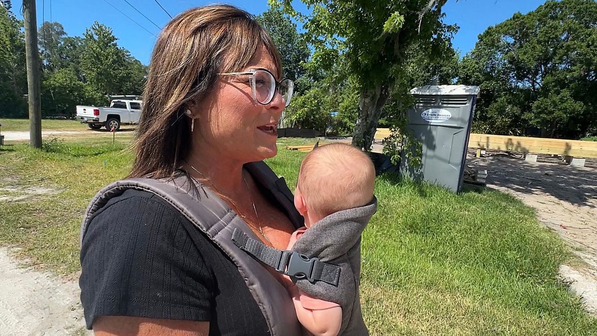 Ryanne Thacker stands in front of her property in New Smyrna Beach where a new home with an elevated foundation is under construction. (Spectrum News/Jeff Allen) 