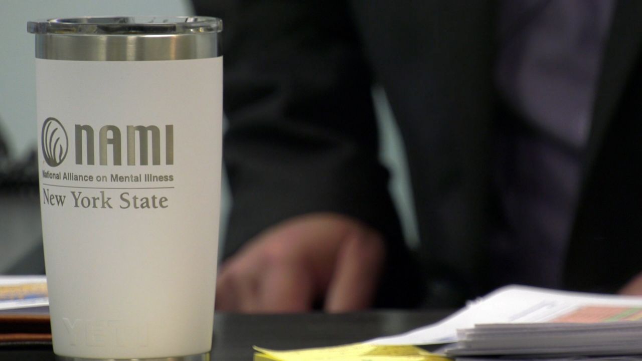 Executive director Jeff Pirrone sits down at his desk in Buffalobehind a National Alliance on Mental Illness mug.