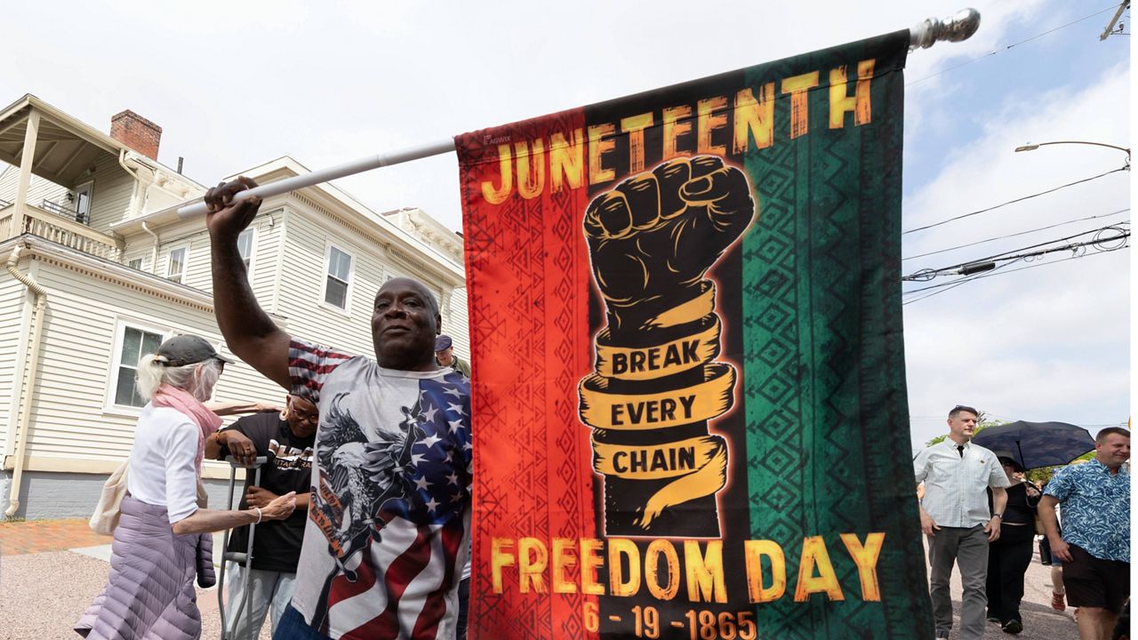 Robert Reid holds a flag during a Juneteenth celebration at the African Burying Ground Memorial Park Thursday, June 19, 2025, in Portsmouth, N.H. (AP Photo/Michael Dwyer)