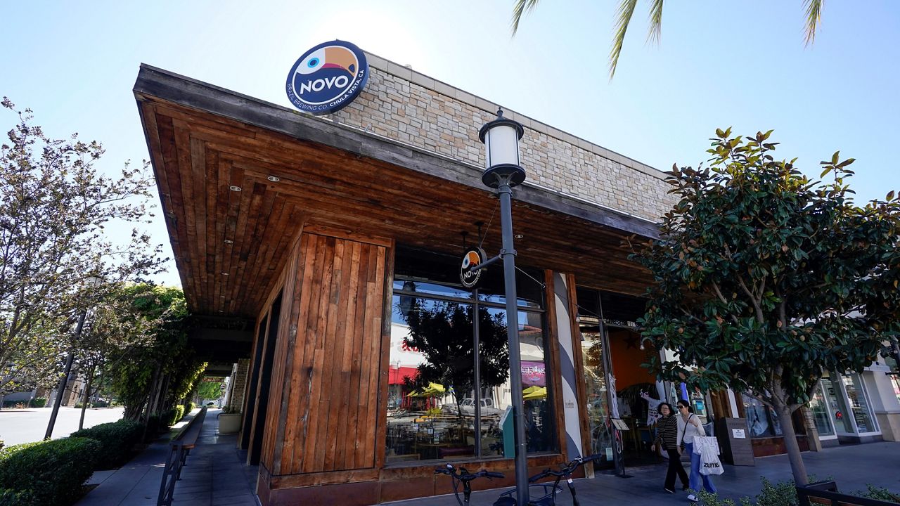 People pass the NOVO Brazil brewery and restaurant Tuesday, Oct. 31, 2023, in Chula Vista, Calif. Four people sustained non-life threatening injuries when a shooter opened fire inside the restaurant on Saturday, south of San Diego, police said. (AP Photo/Gregory Bull)