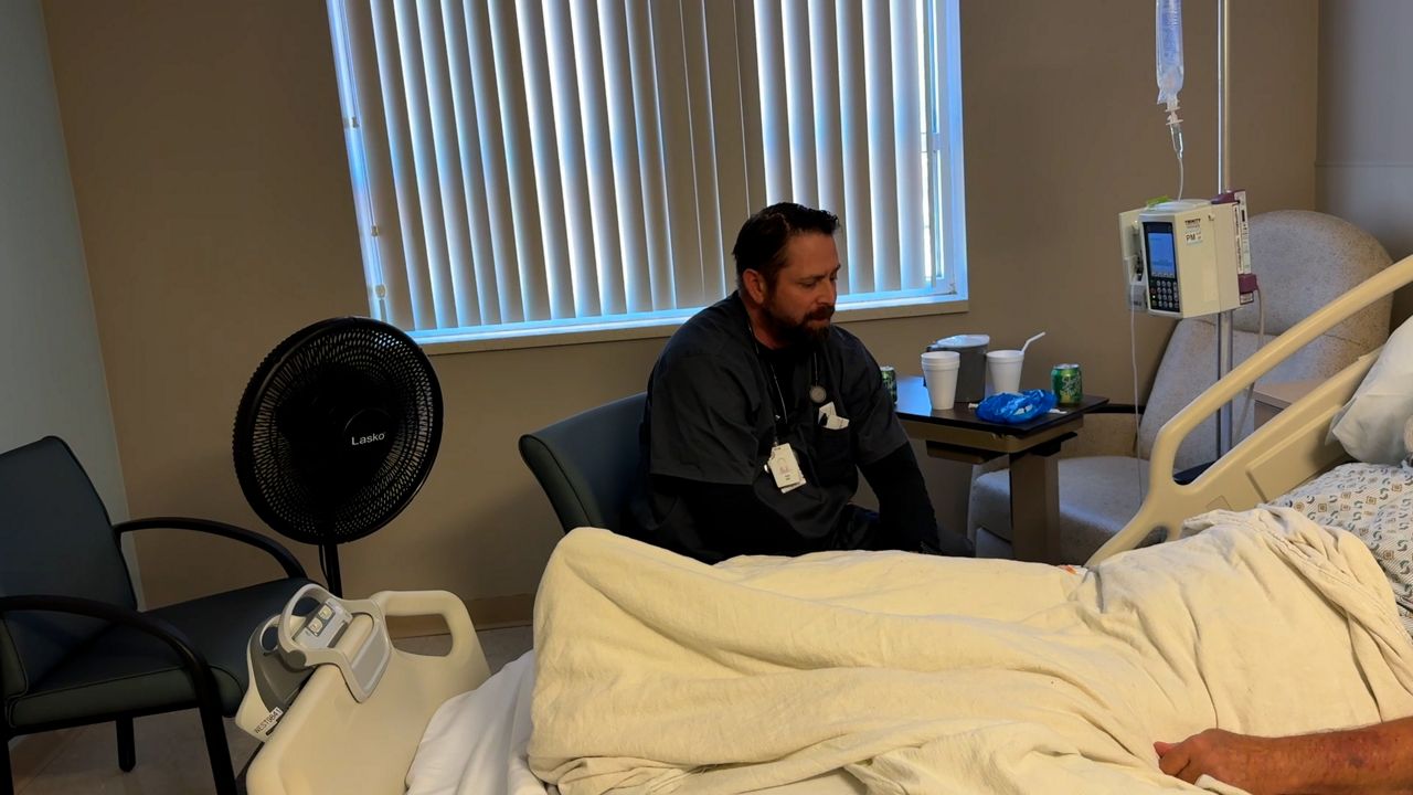 Eric Snyder, an acute care nurse practitioner at Twin City Medical Center, sits next to one of his patients. 