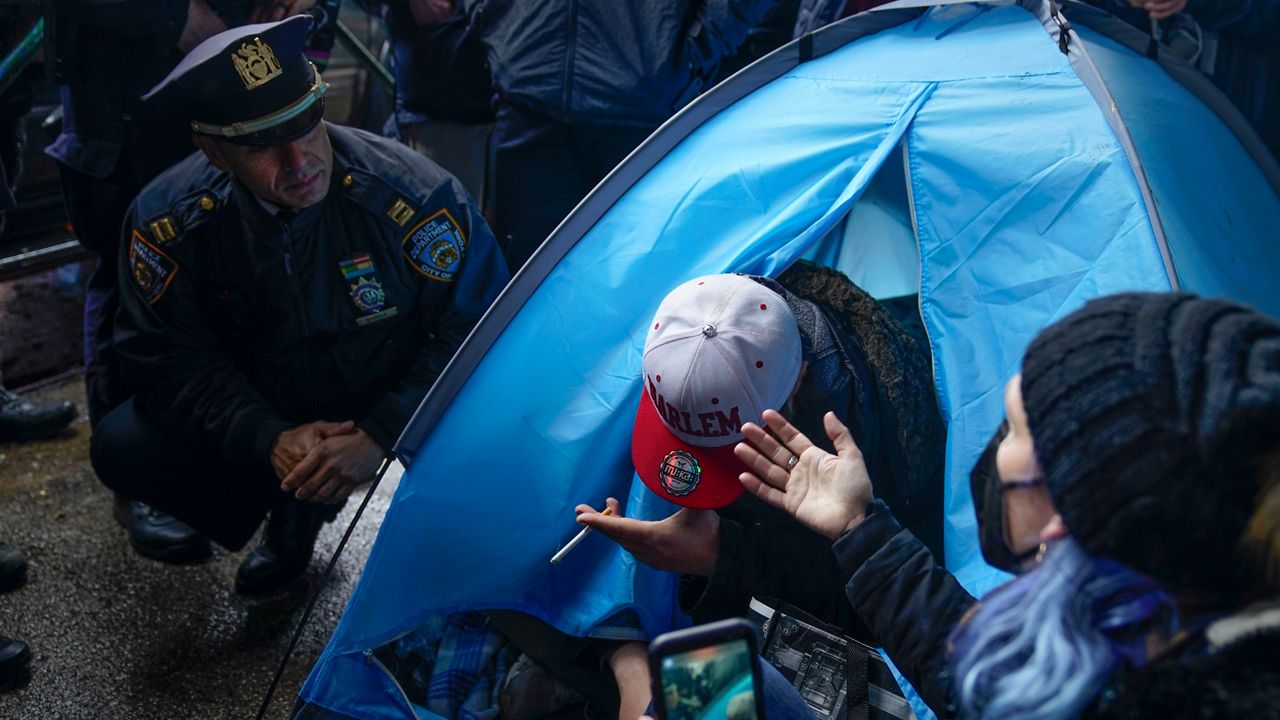 Supporters try to help as Johnny Grimma, center, who is homeless and lives in a tent, talks with police as they attempt to move him at a small homeless encampment in New York, Wednesday, April 6, 2022. (AP Photo/Seth Wenig)