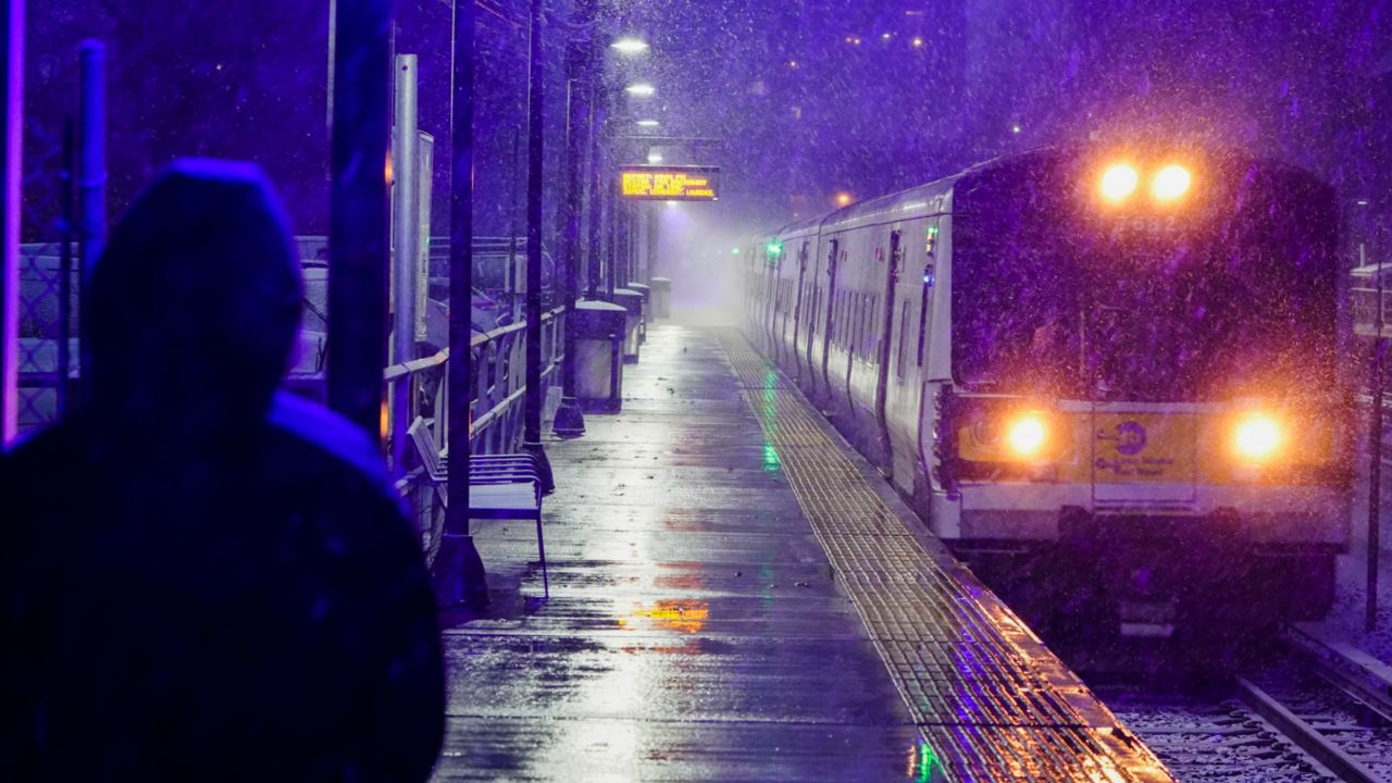 A woman waits for a Long Island Rail Road train in the Queens borough of New York as snow falls at the start of an oncoming snow storm on Wednesday, Dec. 16, 2020.