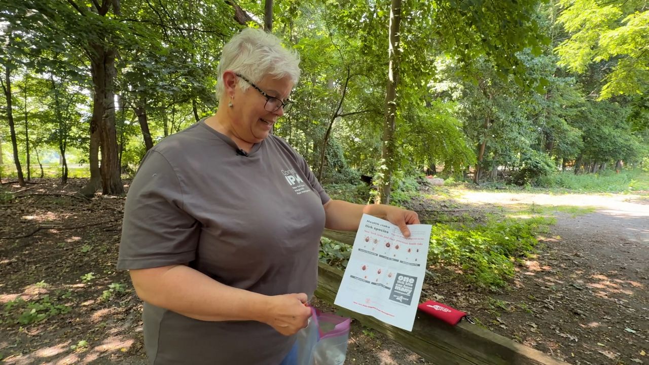 Regina Clinton showing a paper with the different types of ticks found in New York state