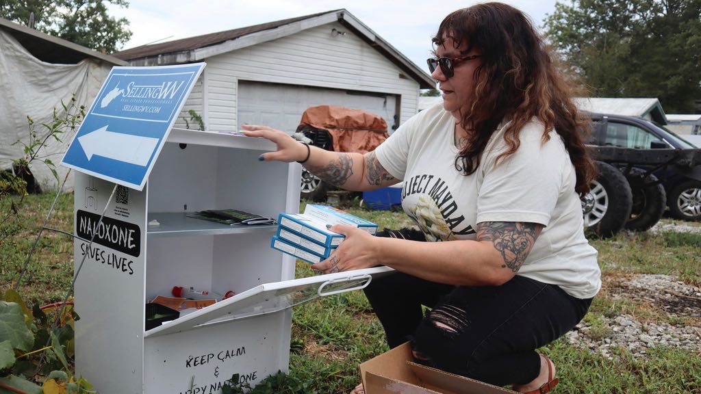 Tasha Withrow, a person in recovery and co-founder of harm reduction organization Project Mayday, refills a new naloxone distribution box in a residental neighborhood of Hurricane, W.Va. on Tuesday, Sept. 24, 2024. (AP Photo/Leah Willingham)