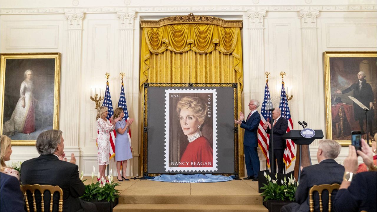 First lady Jill Biden, Postmaster General and Chief Executive Officer Louis DeJoy, Ronald Reagan Presidential Foundation and Institue Board of Trustees Chairman Fred Ryan, and Mrs. Reagan's niece Anne Peterson, unveils a new U.S. Postal Service stamp of former first lady Nancy Reagan in the East Room of the White House, Monday, June 6, 2022, in Washington. (AP Photo/Andrew Harnik)