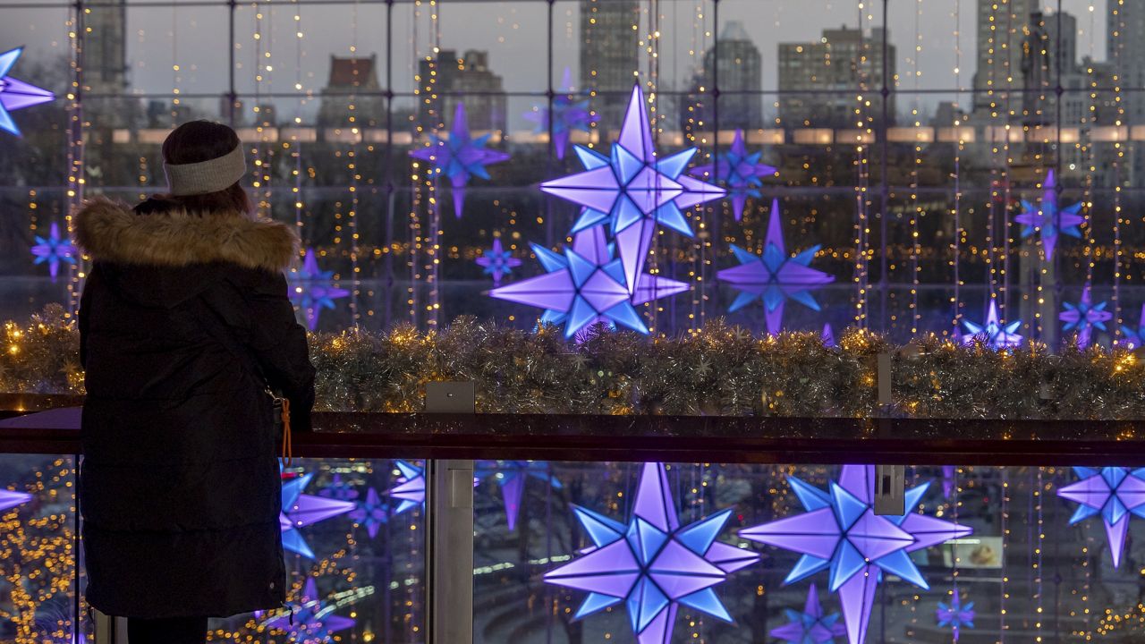 A person views lights in front of the New York skyline at The Shops at Columbus Circle, Thursday, Dec. 12, 2024, in New York. (AP Photo/Julia Demaree Nikhinson)