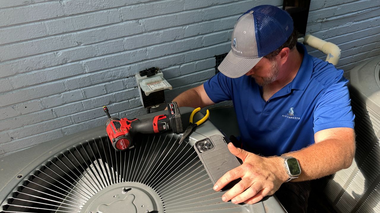 Air Experts technician Nick Howard inspects an air conditioning unit outside a Raleigh home. (Spectrum News 1/Ryan Hayes-Owens)