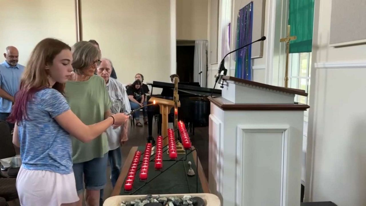 Claire Keith, 13, lights a candle at Royal Lane Baptist Church on Wednesday, July 9, 2025, during a vigil for the deadly floods in the Texas Hill Country. (Spectrum News 1/Valencia Jones)