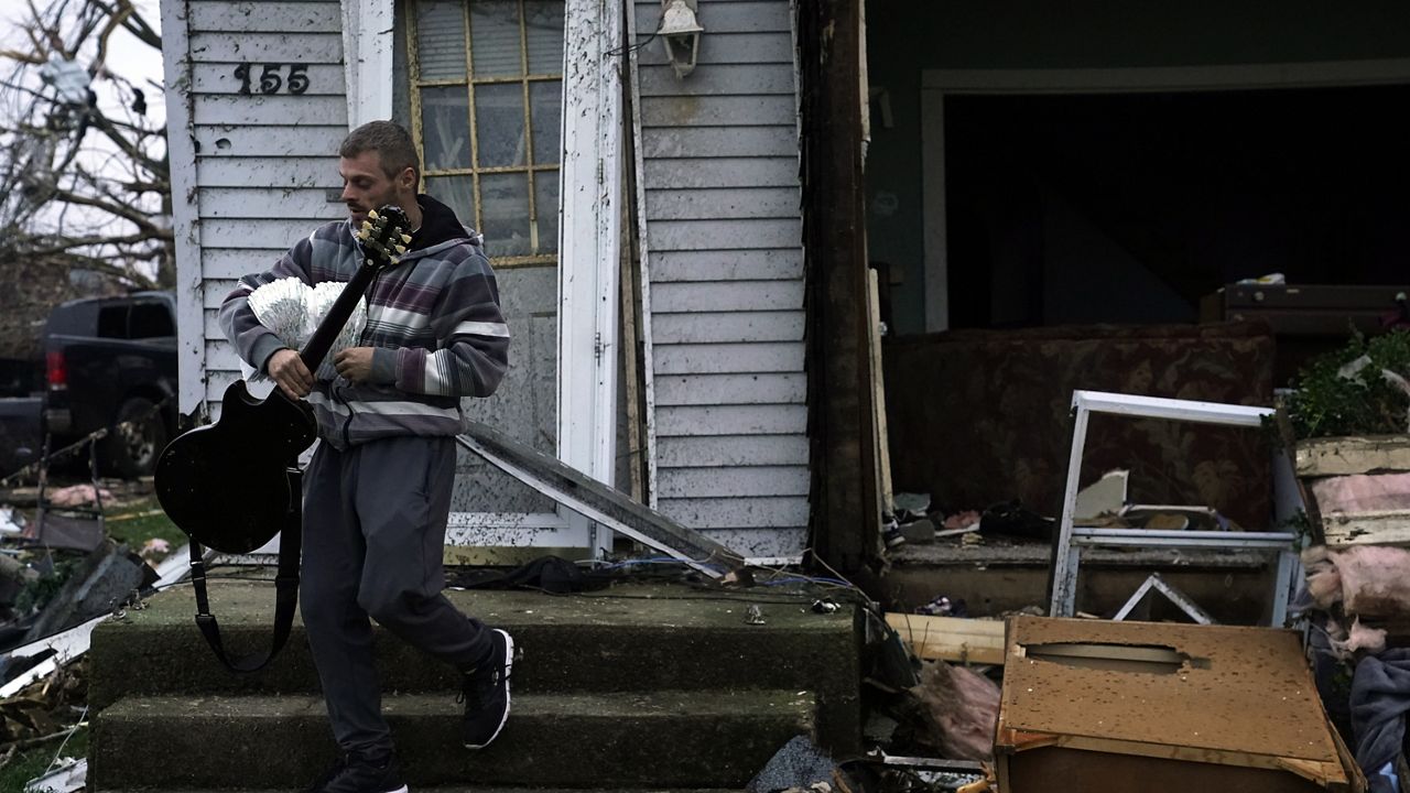 Blaine Schmidt holds his guitar near his damaged home Friday in Lakeview, Ohio.