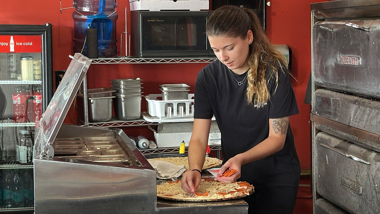 Ashley McCauley, a manager at Bill’s Pizza on Old Orchard Street in Old Orchard Beach, prepares a pizza for the oven Tuesday. She and other managers at the popular pizza shop said trade wars with Canada don’t seem to have stopped tourists from coming to town. (Spectrum News/Sean Murphy)
