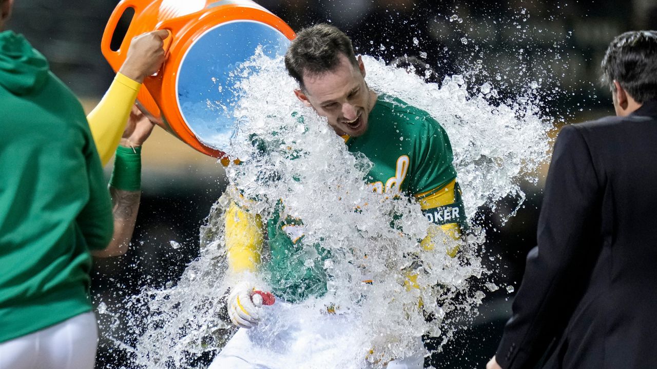 Oakland Athletics' Brent Rooker is doused with iced water by teammates after hitting the game-winning, three-run home run against the Texas Rangers during the 10th inning of a baseball game in Oakland, Calif., Friday, May 12, 2023. (AP Photo/Godofredo A. Vásquez)