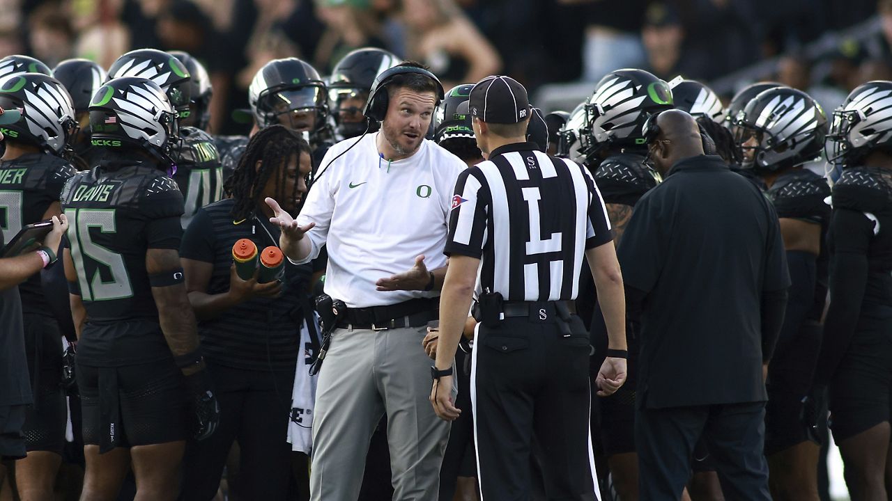 Oregon head coach Dan Lanning, center left, talks with a referee, center right, during an NCAA college football game against Ohio State, Saturday, Oct. 12, 2024, in Eugene, Ore. (AP Photo/Lydia Ely)