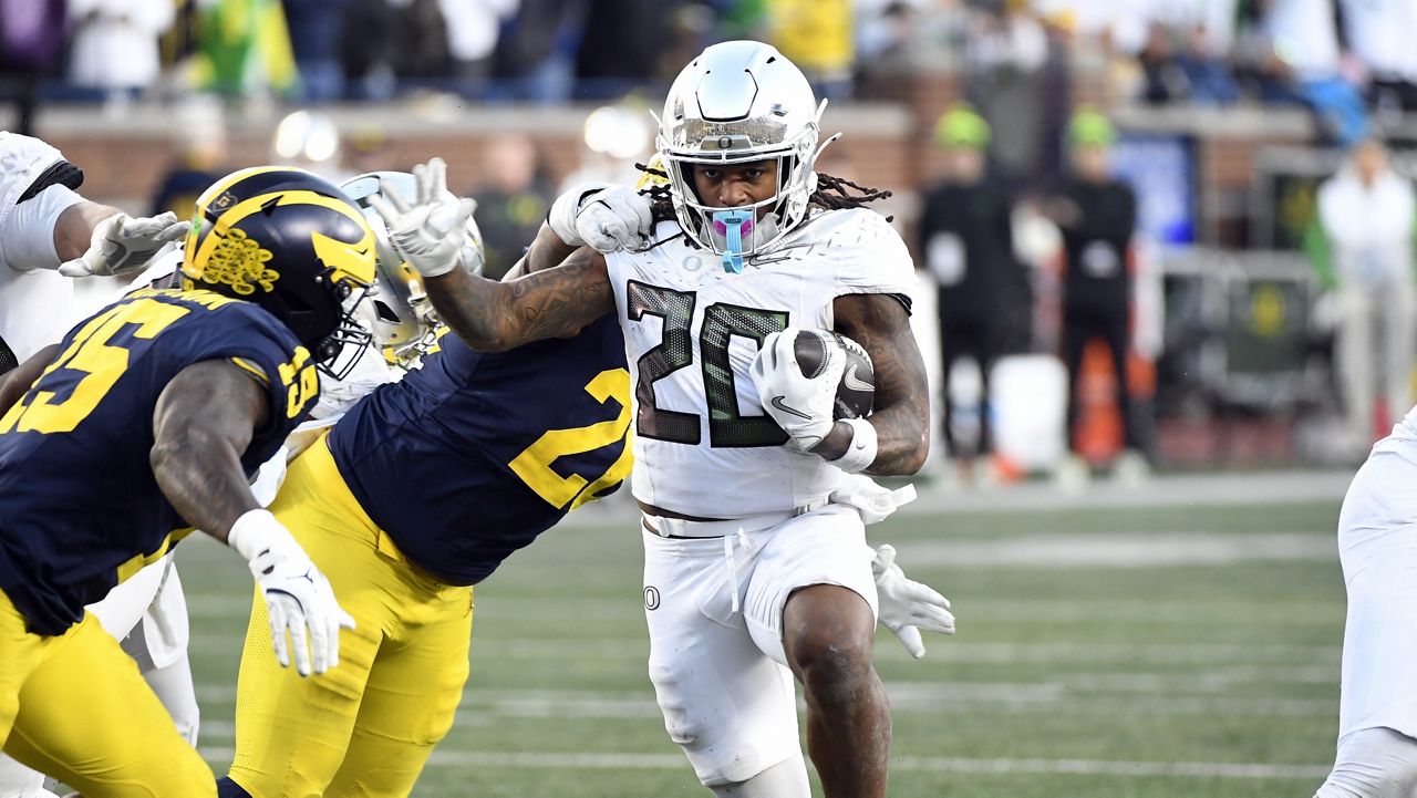 Oregon running back Jordan James (20) runs with the ball and is chased by Michigan linebacker Ernest Hausmann (15) and defensive lineman Rayshaun Benny (26) during the second half of an NCAA college football game, Saturday, Nov. 2, 2024, in Ann Arbor, Mich. Oregon defeated Michigan 38-17. (AP Photo/Jose Juarez)