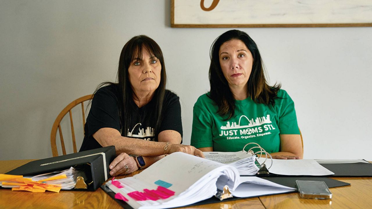 Karen Nickel, left, and Dawn Chapman flip through binders full of government documents about St. Louis County sites contaminated by nuclear waste left over from World War II. Nickel and Chapman founded Just Moms STL to advocate for the community to federal environmental and energy officials (Theo Welling/Riverfront Times via Missouri Independent).