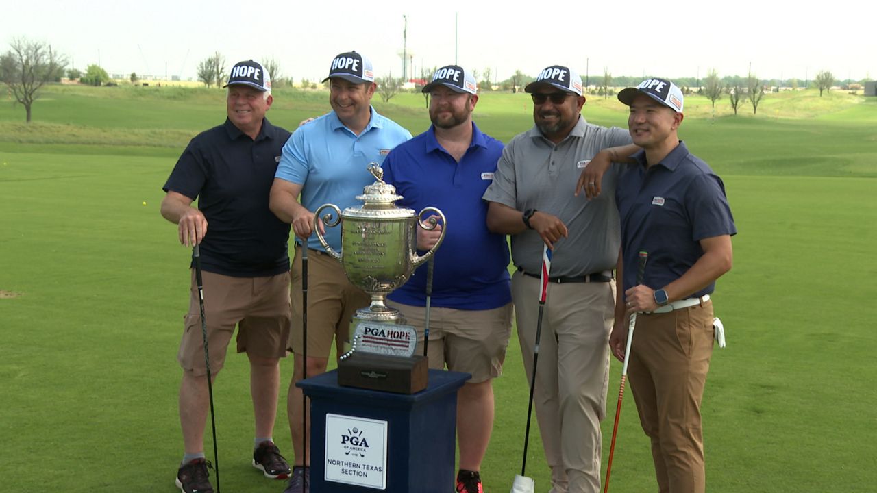 Participants in the PGA HOPE program pose with a trophy. (Spectrum News 1/Adam Rossow)