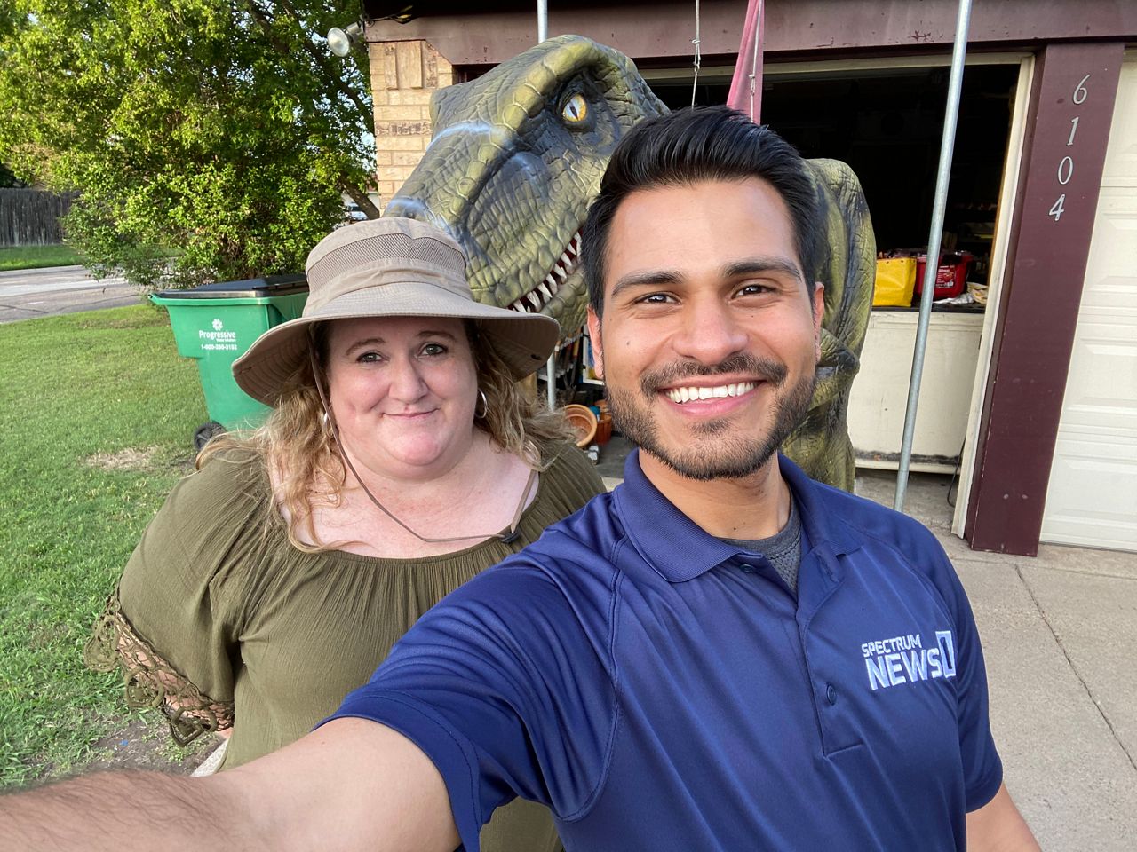 Pictured is Spectrum News 1 Texas human interest reporter Lupe Zapata and Watauga, Texas, resident Krysti Burton with Norman the 8-foot-tall dinosaur. Burton is the owner of Dino-Adventure, offering the realistic human-operated walking dinosaur for parties and events. (Spectrum News 1/ Lupe Zapata)