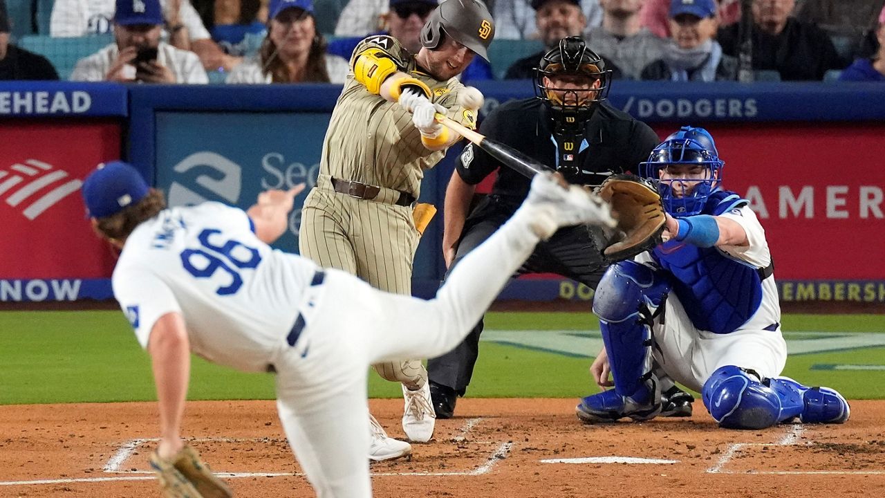 San Diego Padres' Jake Cronenworth, second from left, hits a two-run home run as Los Angeles Dodgers starting pitcher Landon Knack, left, washes along with catcher Will Smith, right, and home plate umpire Tripp Gibson during the second inning of a baseball game, Tuesday, Sept. 24, 2024, in Los Angeles. (AP Photo/Mark J. Terrill)