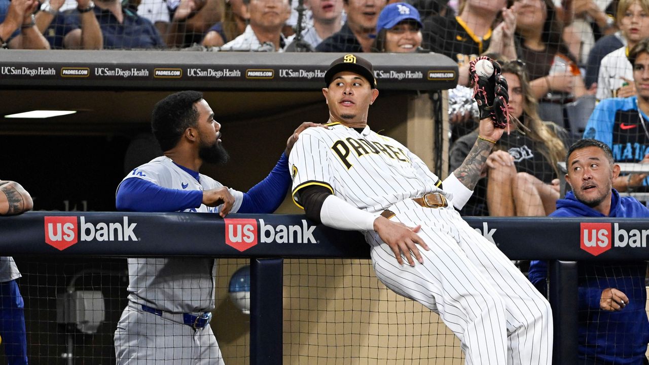 Los Angeles Dodgers' Teoscar Hernández (37) congratulates San Diego Padres third baseman Manny Machado (13) after he made a catch on a foul ball hit by Kiké Hernandez (8) during the fourth inning of a baseball game Tuesday, July 30, 2024, in San Diego. (AP Photo/Denis Poroy)