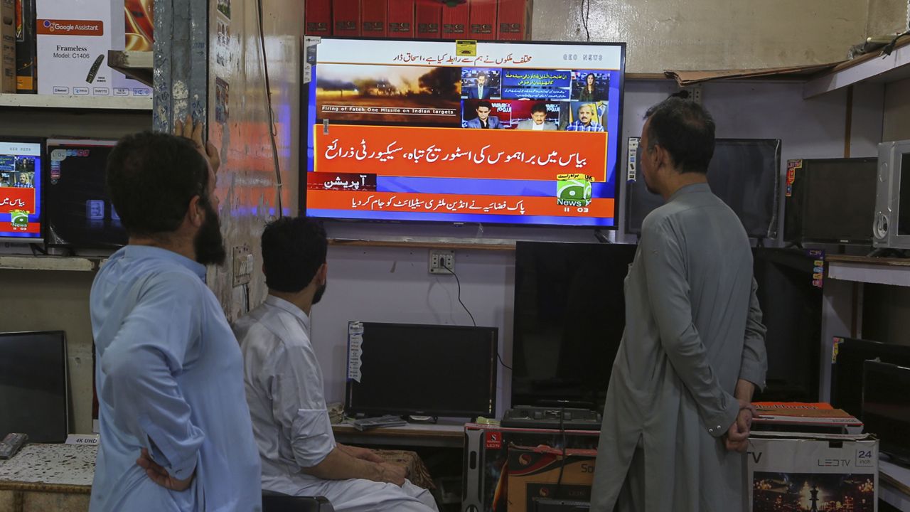 Shopkeepers watch a news channel telecasting ongoing military tension between Pakistan and India, at a shop in Peshawar, Pakistan, Saturday, May 10, 2025. (AP Photo/Muhammad Sajjad)