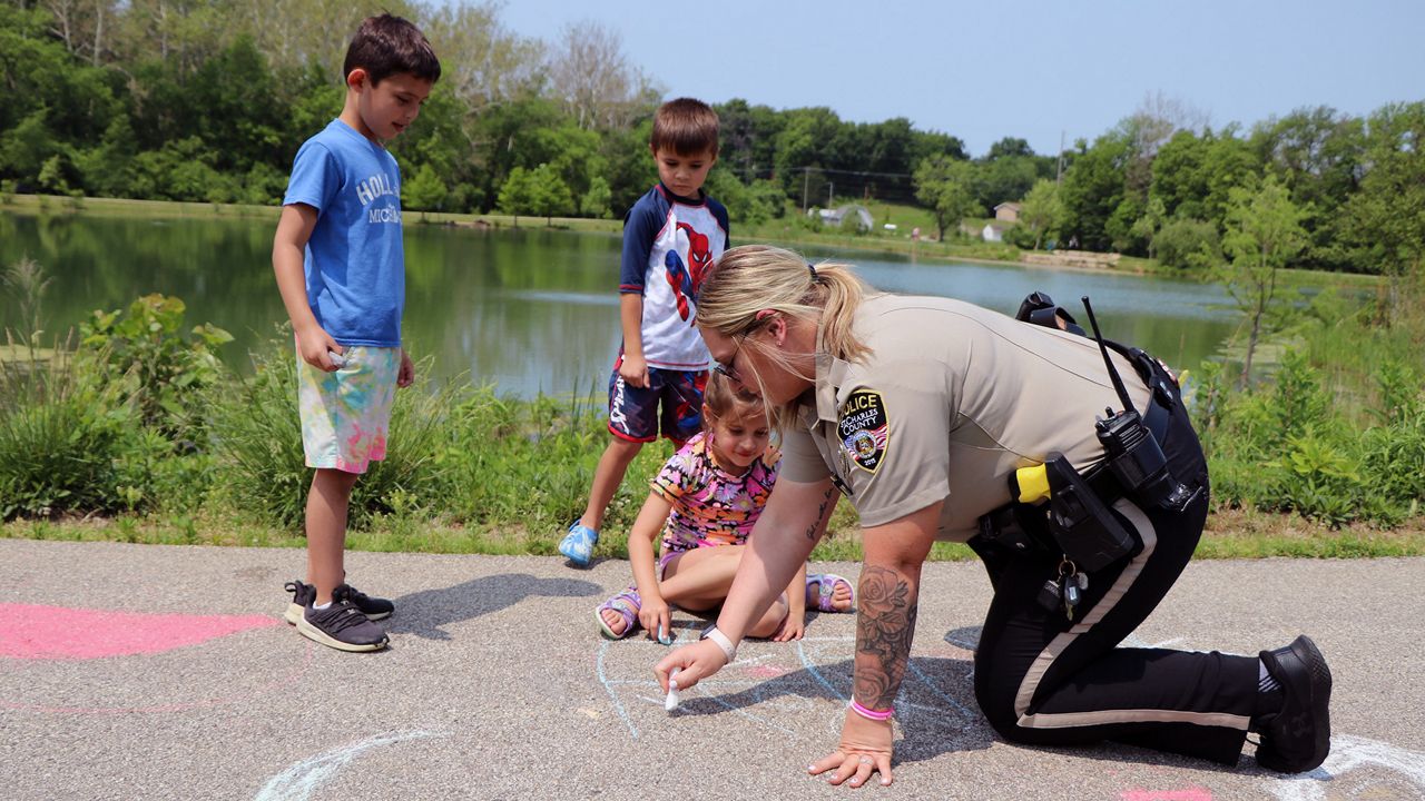 St. Charles County SRO Jaclyn Gubricky plays tic-tac-toe with kindergartners from Immanuel Lutheran School St. Charles Thursday, May 18, during a field trip at Veterans Tribute Park. (Spectrum News/Elizabeth Barmeier)