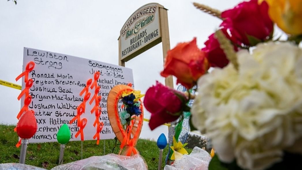 Numerous bouquets of flowers and tributes to the victims drip with Monday morning’s light drizzle on the side of Lincoln Street in Lewiston in front of Schemengees, one of the sites of last week’s mass killings by Robert Card. (Russ Dillingham/Sun Journal).