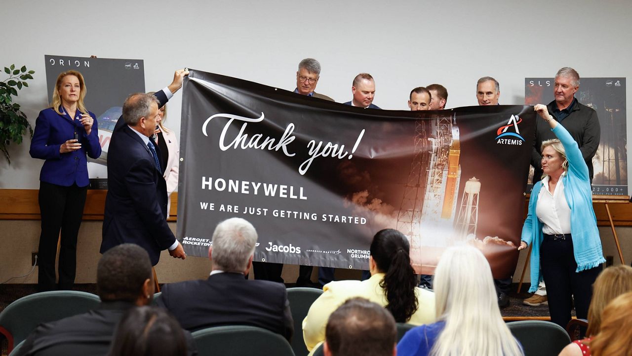 Dignitaries unveil a banner thanking employees during a presentation ceremony at Honeywell Aerospace on Thursday in Clearwater. [ JEFFEREE WOO | Times ]