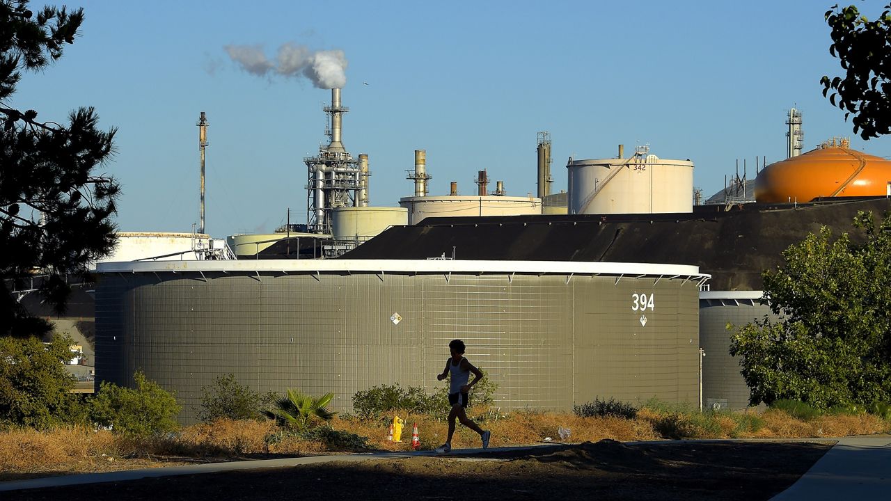 A jogger runs in front of the Phillips 66 refinery, July 16, 2014, in the Wilmington area of Los Angeles. (AP Photo/Mark J. Terrill, File)