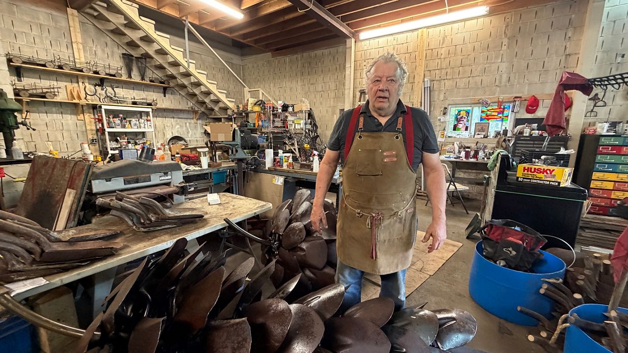 Patrick Plourde stands next to two other pinecone works that are similar, but not the same, as those set to be installed outside the Blaine House. (Spectrum News/Susan Cover)