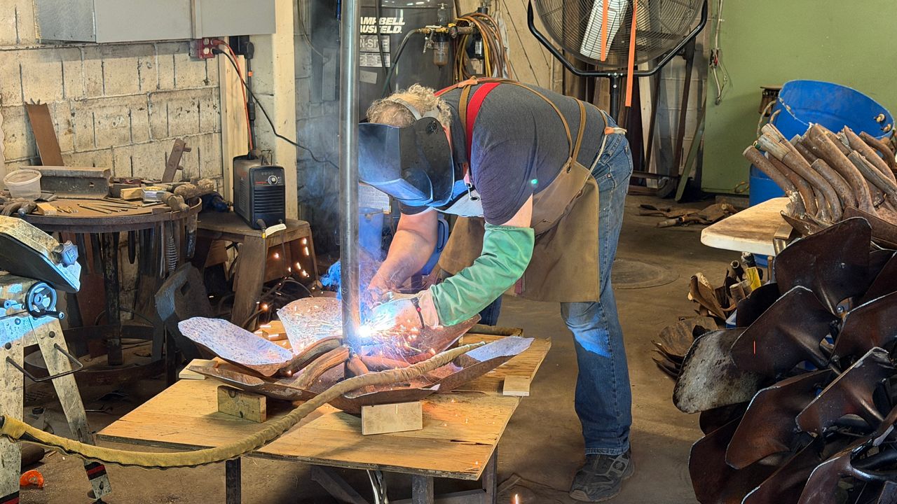Artist Patrick Plourde welds inside his studio in Lisbon Falls. (Spectrum News/Susan Cover)