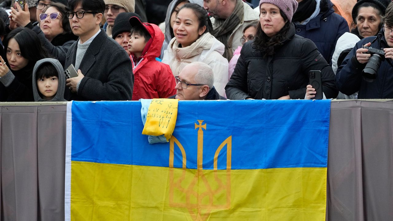 Fithful display an Ukrainian flag as they wait Pope Leo XIV's Urbi et Orbi (Latin for 'to the city and to the world' Christmas' ) day blessing from the main balcony of St. Peter's Basilica at the Vatican, Thursday, Dec. 25, 2025. (AP Photo/Gregorio Borgia)