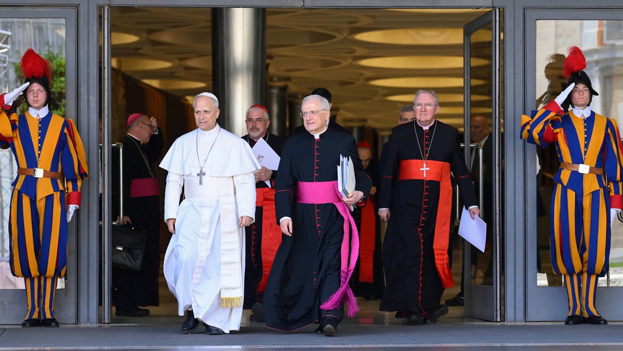 Pope Leo XIV, left, is flanked by Monsignor Leonardo Sapienza, second from left, after his meeting with the College of Cardinals in the New Synod Hall at the Vatican, Saturday, May 10, 2025. (Vatican Media via AP)