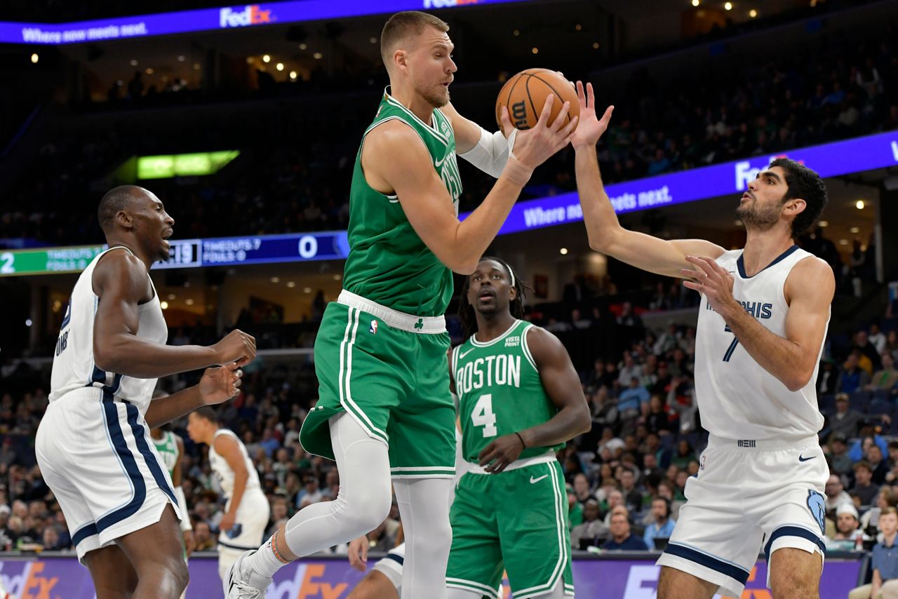 Boston Celtics center Kristaps Porzingis, handles the ball against Memphis Grizzlies forward Santi Aldama (7) in the first half of an NBA basketball game Sunday, Nov. 19, 2023, in Memphis, Tenn. (AP Photo/Brandon Dill)