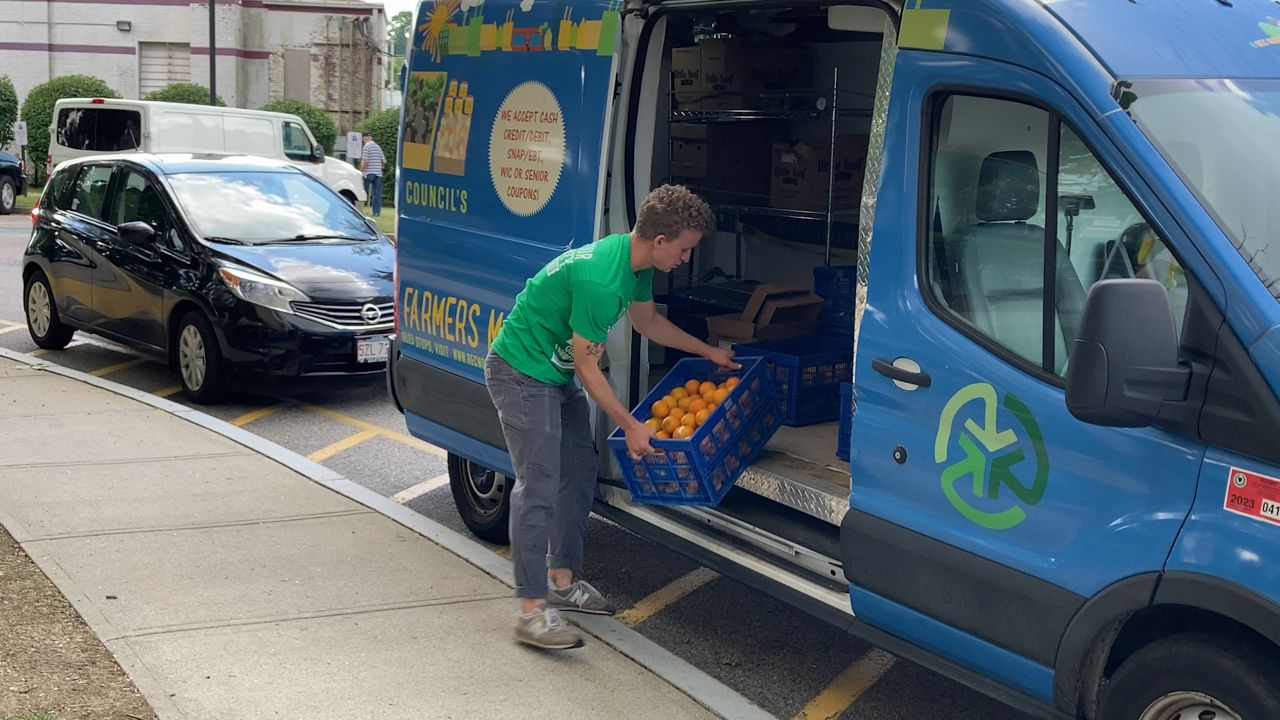An REC employee carries a crate of oranges out of the Mobile Farmers Market van. (Spectrum News 1/Devin Bates)