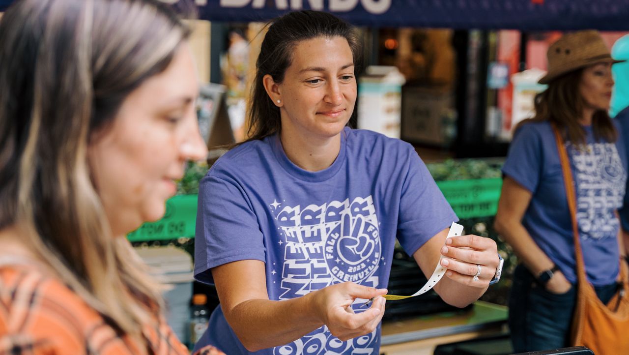 A volunteer hands out a wristband at the 2023 Fall for Greenville festival. 