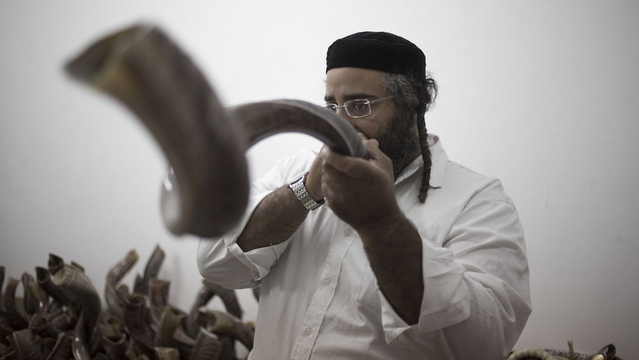 In this Monday, Sept. 22, 2014 photo, Moshe Manos tests a shofar, or ram's horn, traditionally used during the Jewish New Year holiday of Rosh Hashana. (AP Photo/Ariel Schalit)