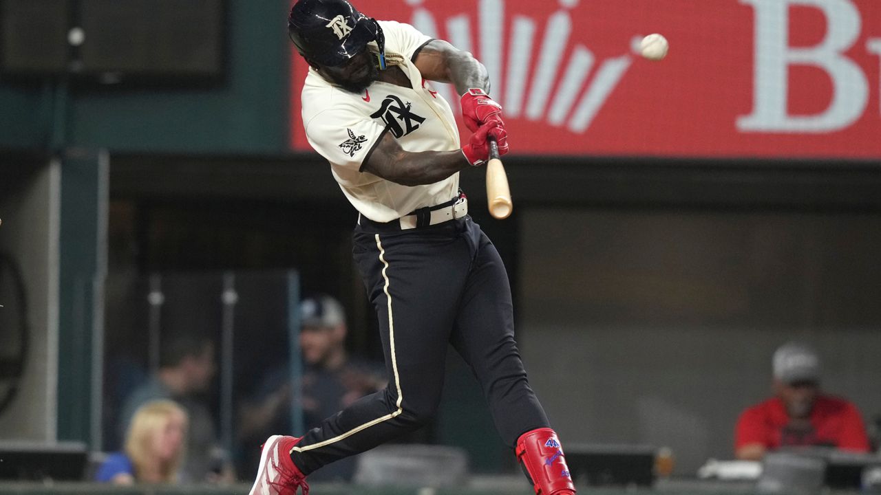 Texas Rangers' Adolis Garcia hits a two-run home run during the fourth inning of a baseball game against the Colorado Rockies in Arlington, Texas, Friday, May 19, 2023. Rangers' Nathaniel Lowe also scored on the play. (AP Photo/LM Otero)