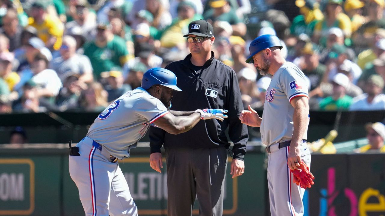 Texas Rangers' Adolis García, left, celebrates with first base coach Corey Ragsdale, right, after hitting an RBI single during the sixth inning of a baseball game against the Oakland Athletics, Thursday, Sept. 26, 2024, in Oakland, Calif. (AP Photo/Godofredo A. Vásquez)